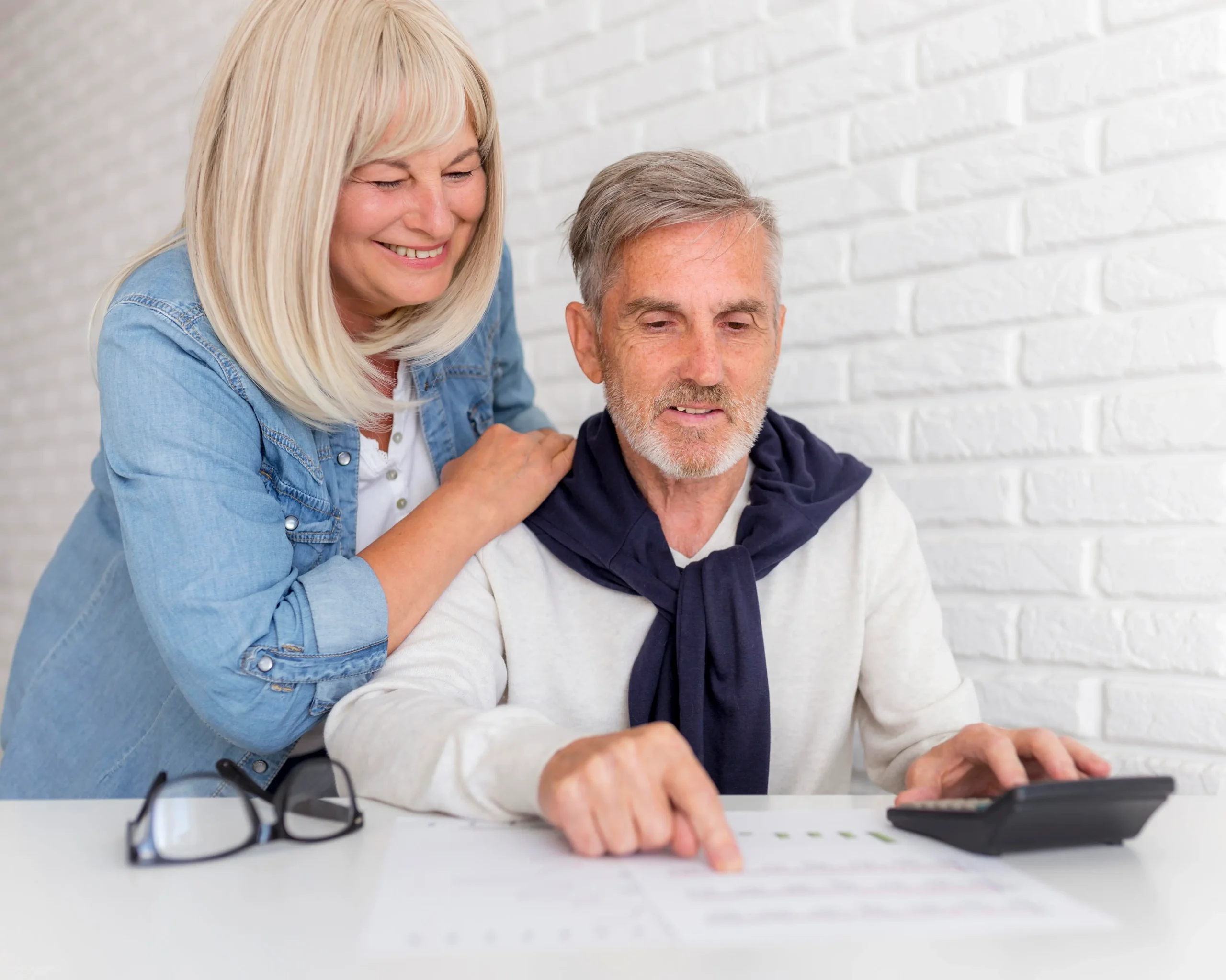 Smiling elderly couple reviewing pension documents together at home.